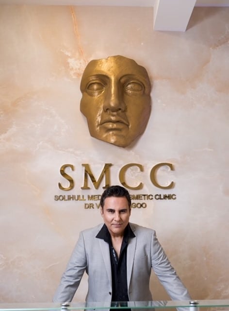 Dr sagoo in front of solihull cosmetic clinic logo
