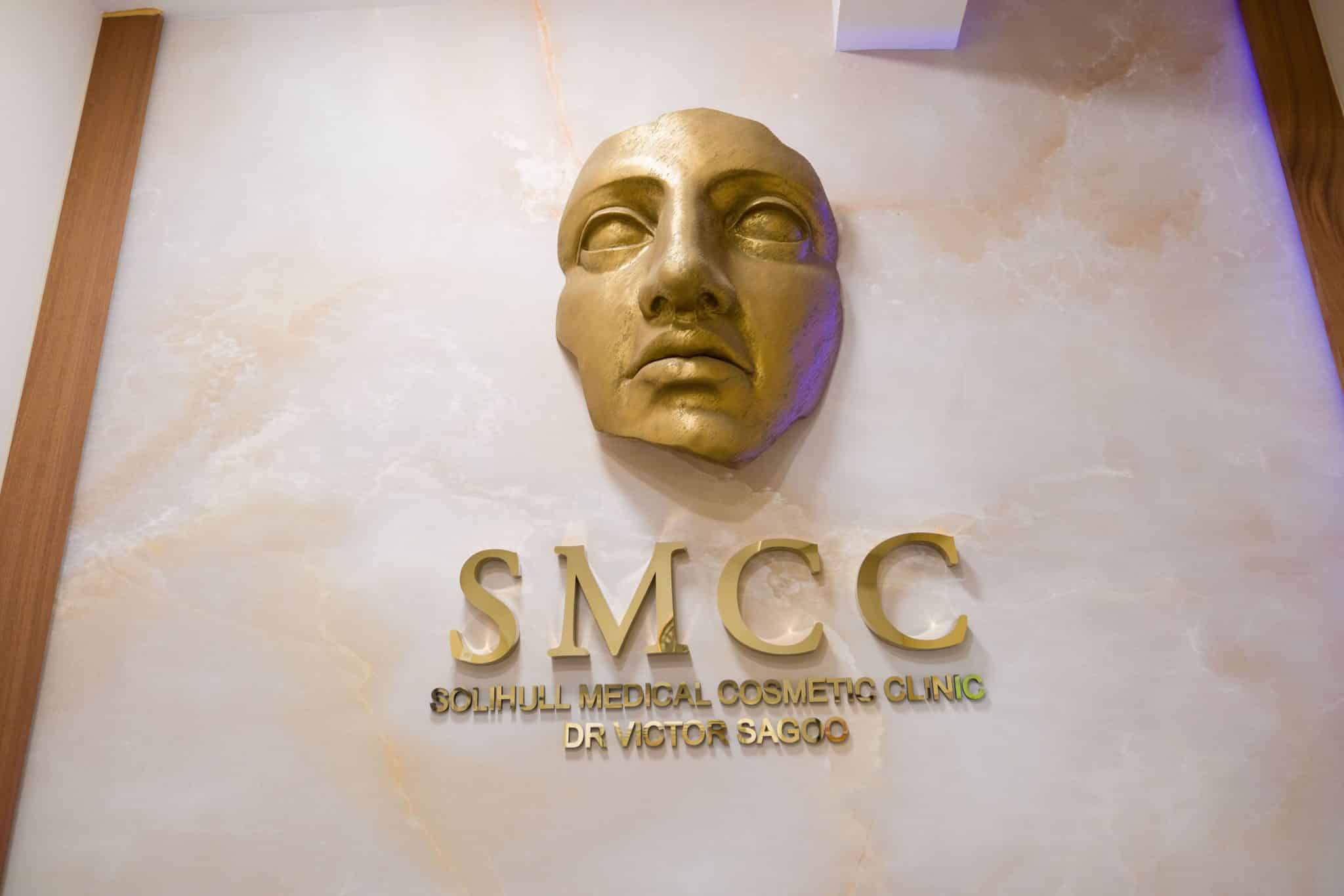 Gold-colored sculpted face mounted on a marble wall above the sign for Solihull Medical Cosmetic Clinic, Dr. Victor Sago.